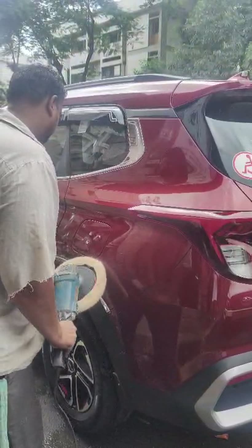 Rotary polisher cutting the rear quarter of a red Kia Sonet