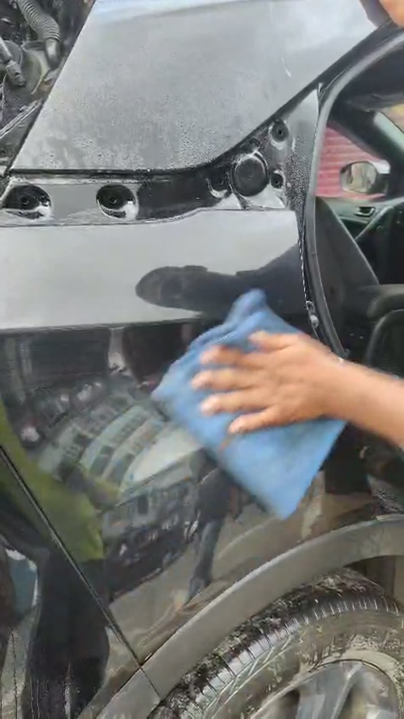 Installer wiping down freshly applied paint protection film on a black car panel