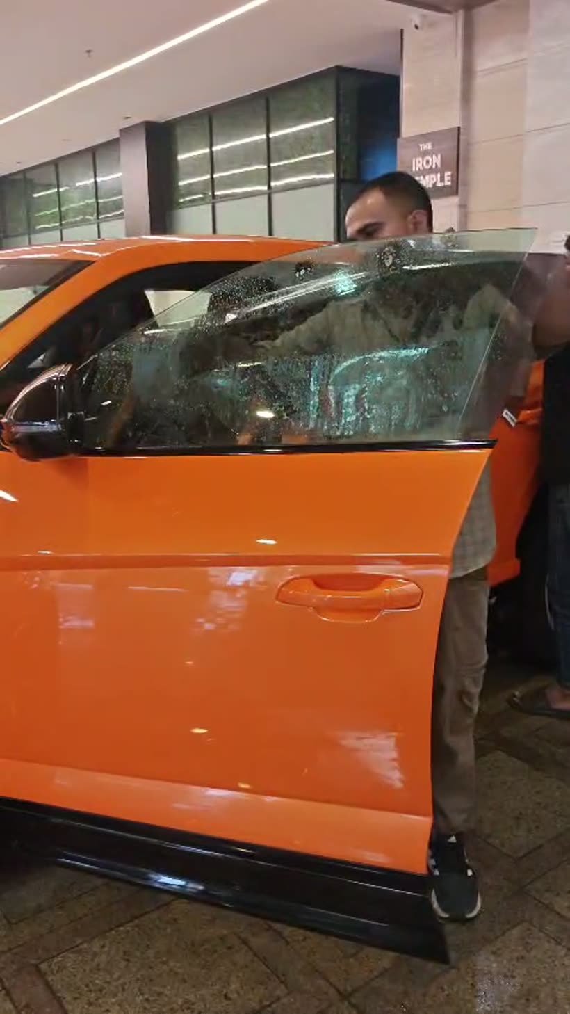 Window film being squeegeed onto the door glass of an orange Audi