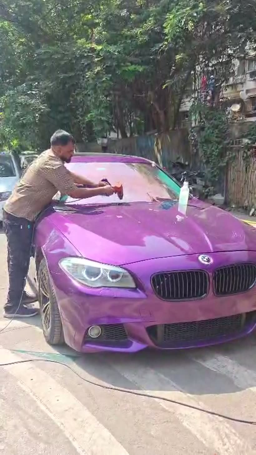 Purple colour-change wrapped BMW 5 Series being buffed by hand